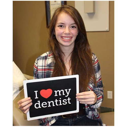 Happy dental patient holding up a sign that reads I love my dentist