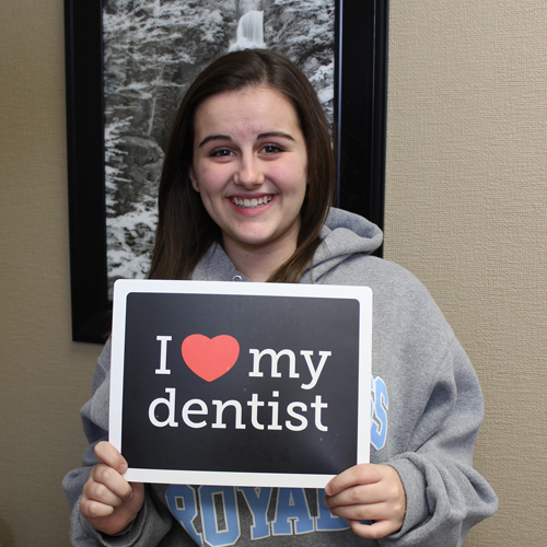 Young woman holding up a sign that reads I love my dentist